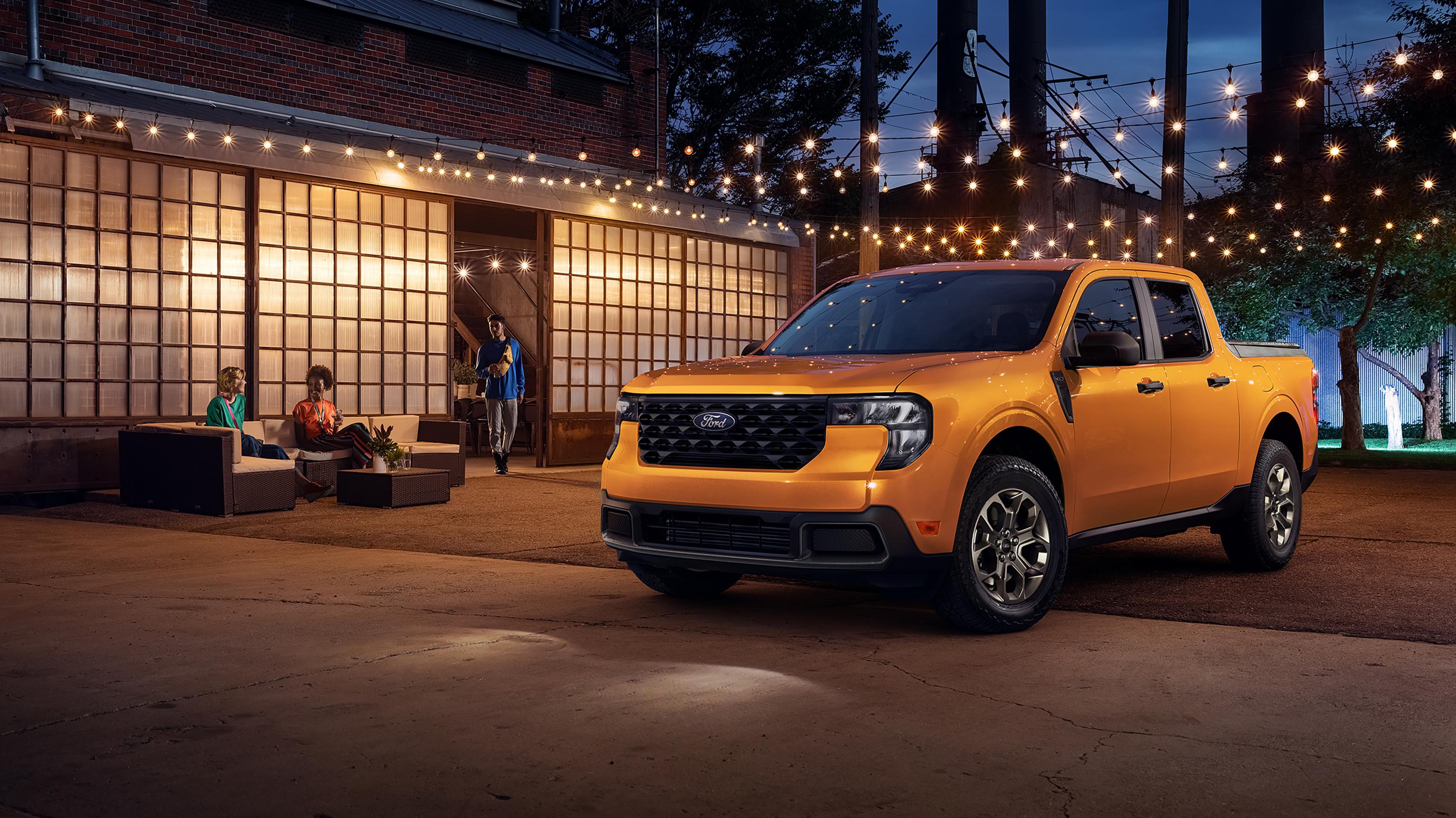 2026 Ford Maverick® XLT model in Orange Fury parked under lights next to a building at night