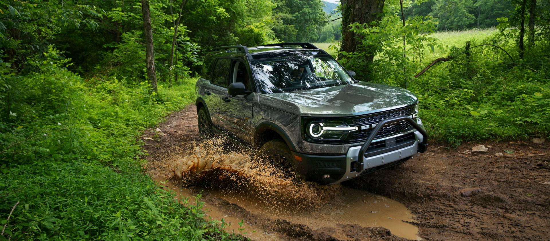 A 2026 Ford Bronco Sport® SUV being driven on a muddy forest track.
