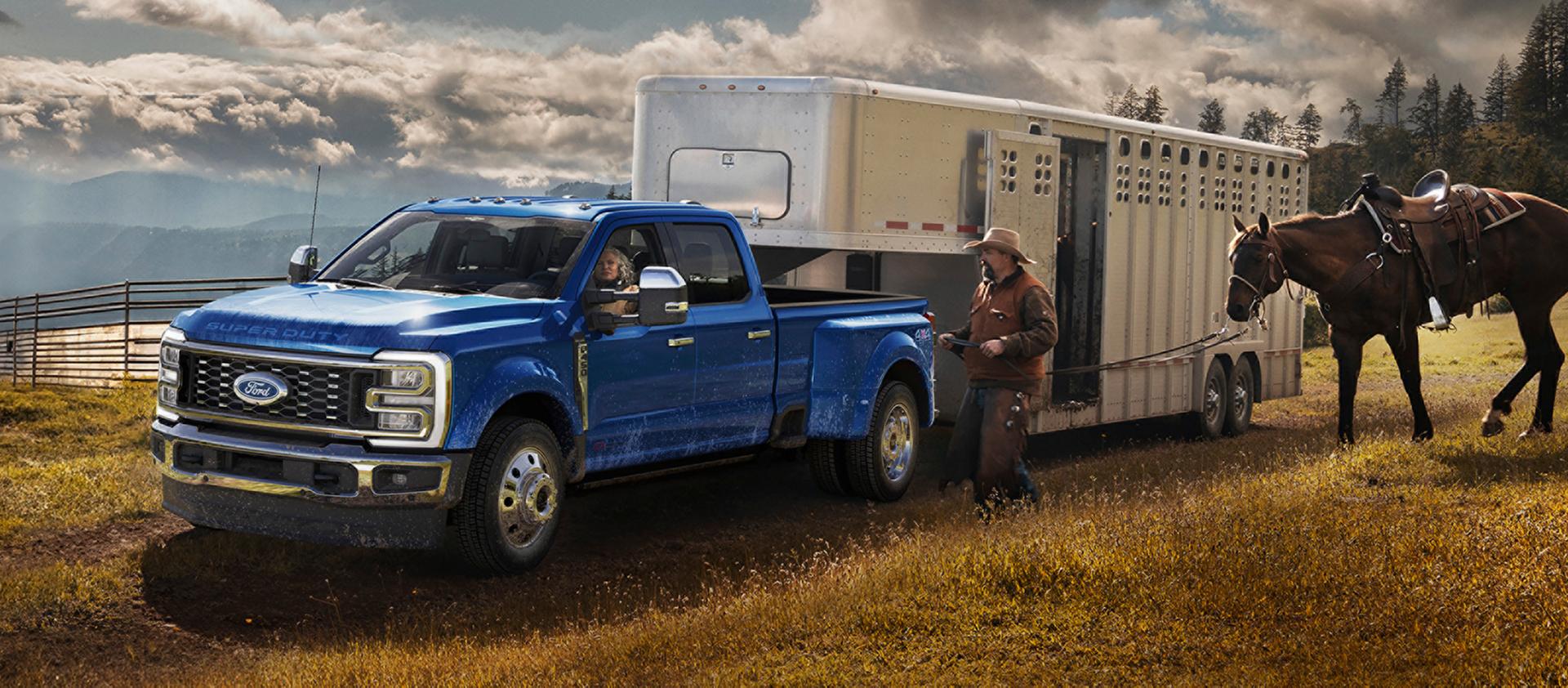 2027 Ford Super Duty® F-450® King Ranch® pickup in Neptune Blue towing a horse carrier on a grassy farm