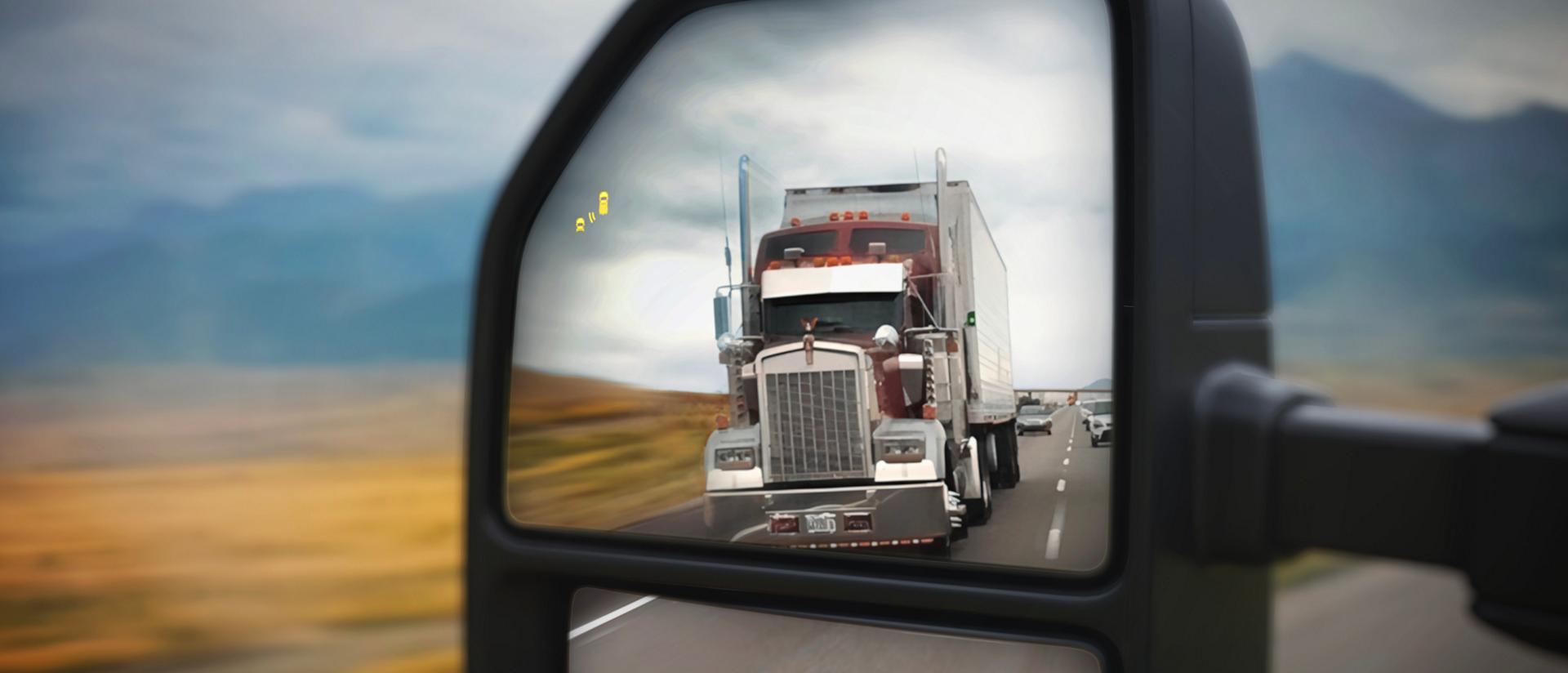View of the 2027 Ford Super Duty® pickup left sideview mirror with a semi truck in the reflection