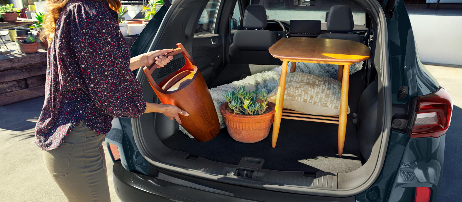 Woman loading items into the cargo area of a 2026 Ford Escape® SUV