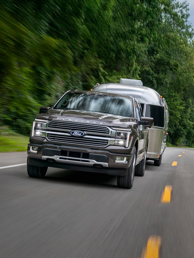 2025 Ford F-150® Platinum® truck in Marsh Gray pulling a camper
