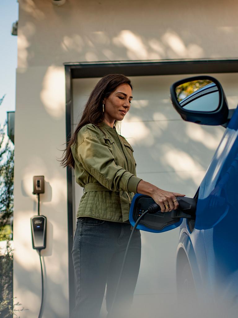 Person plugging a home charger into a 2026 Ford Mustang Mach-E® SUV parked in a driveway