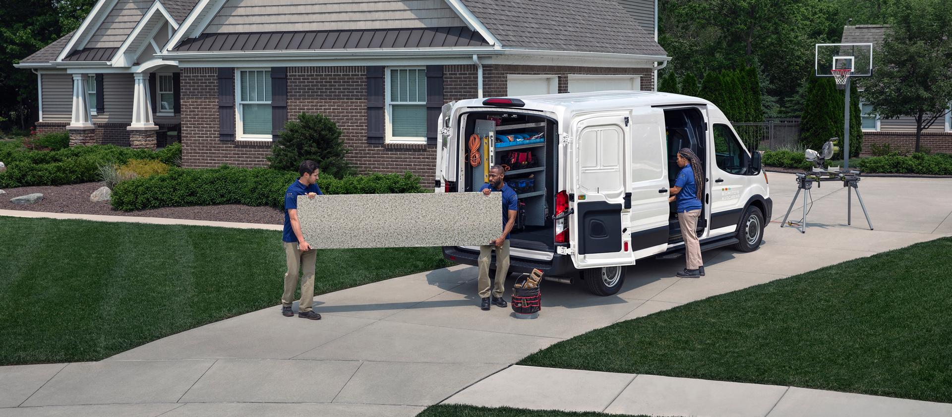 Service workers unloading equipment from a white 2027 Ford Transit® Cargo Van in a driveway