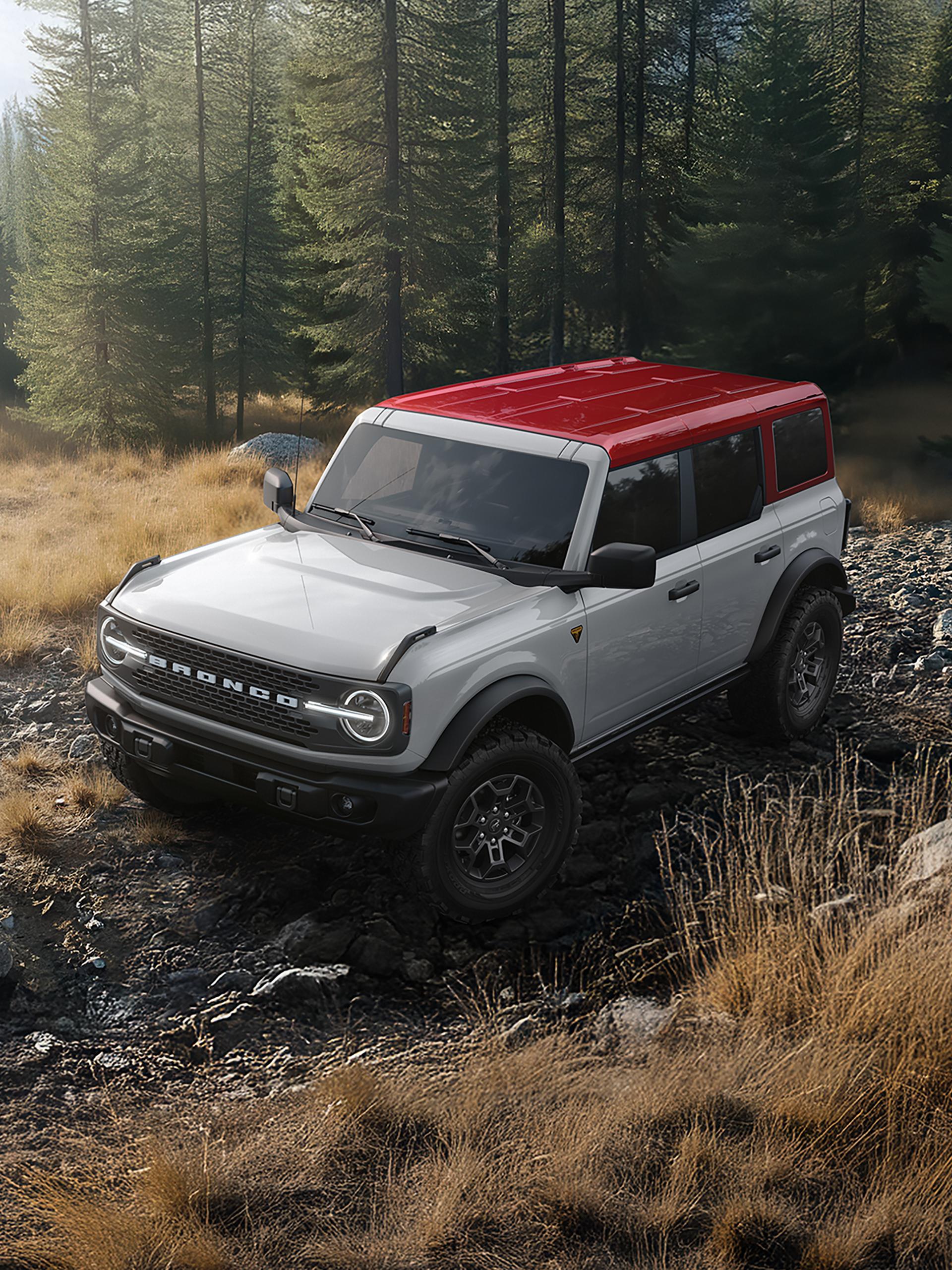 A 2026 Ford Bronco® SUV on a muddy path, with a dark-coloured body and a white roof