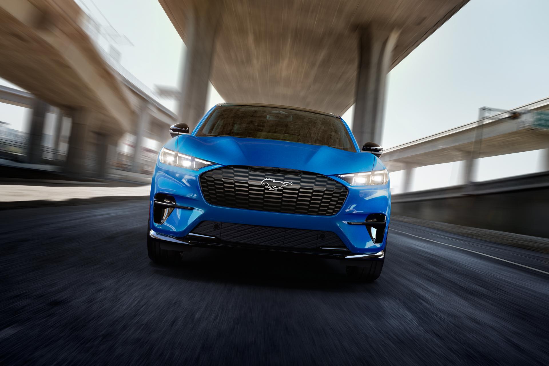 Front view of a 2025 Mustang Mach-E® GT model being driven on a freeway with a blurred background