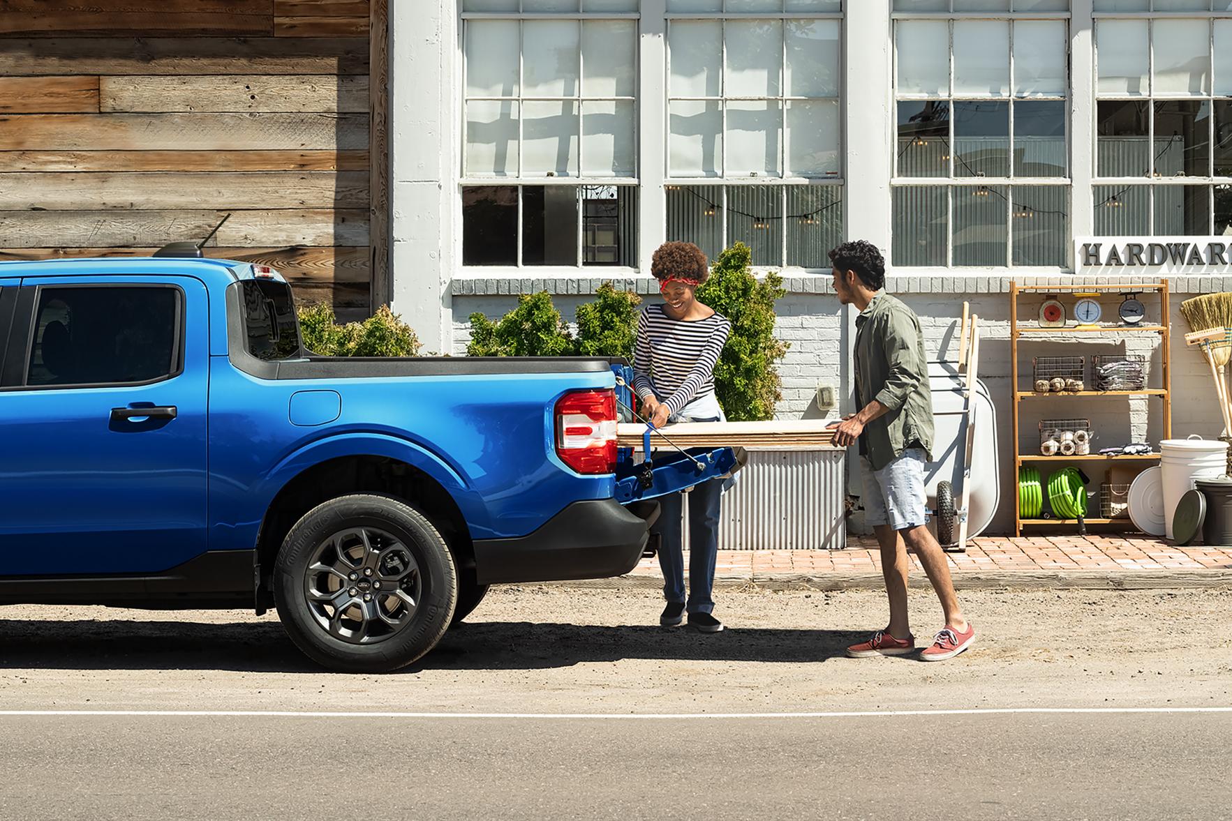 Two people load timbre into the back of a Ford Maverick truck.