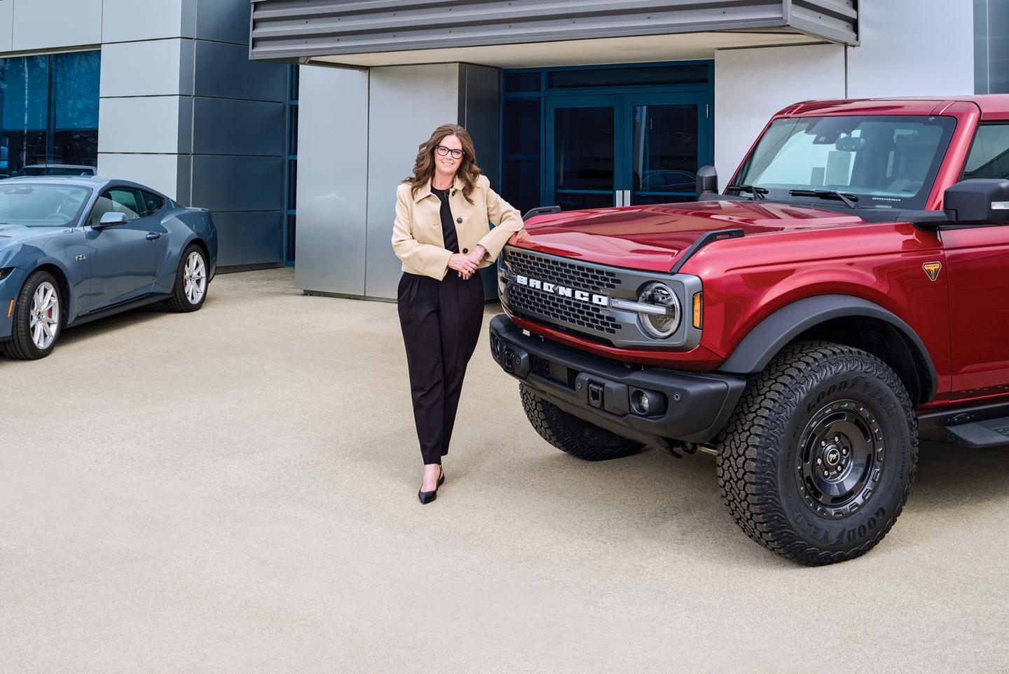 Person leaning on a Bronco at a Ford dealership.