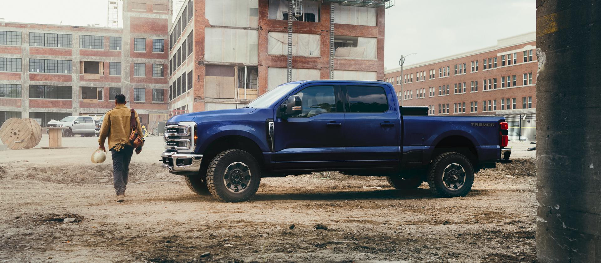 A person walking away from their 2026 Ford Super Duty® F-250® Lariat® in Argon Blue on a construction site