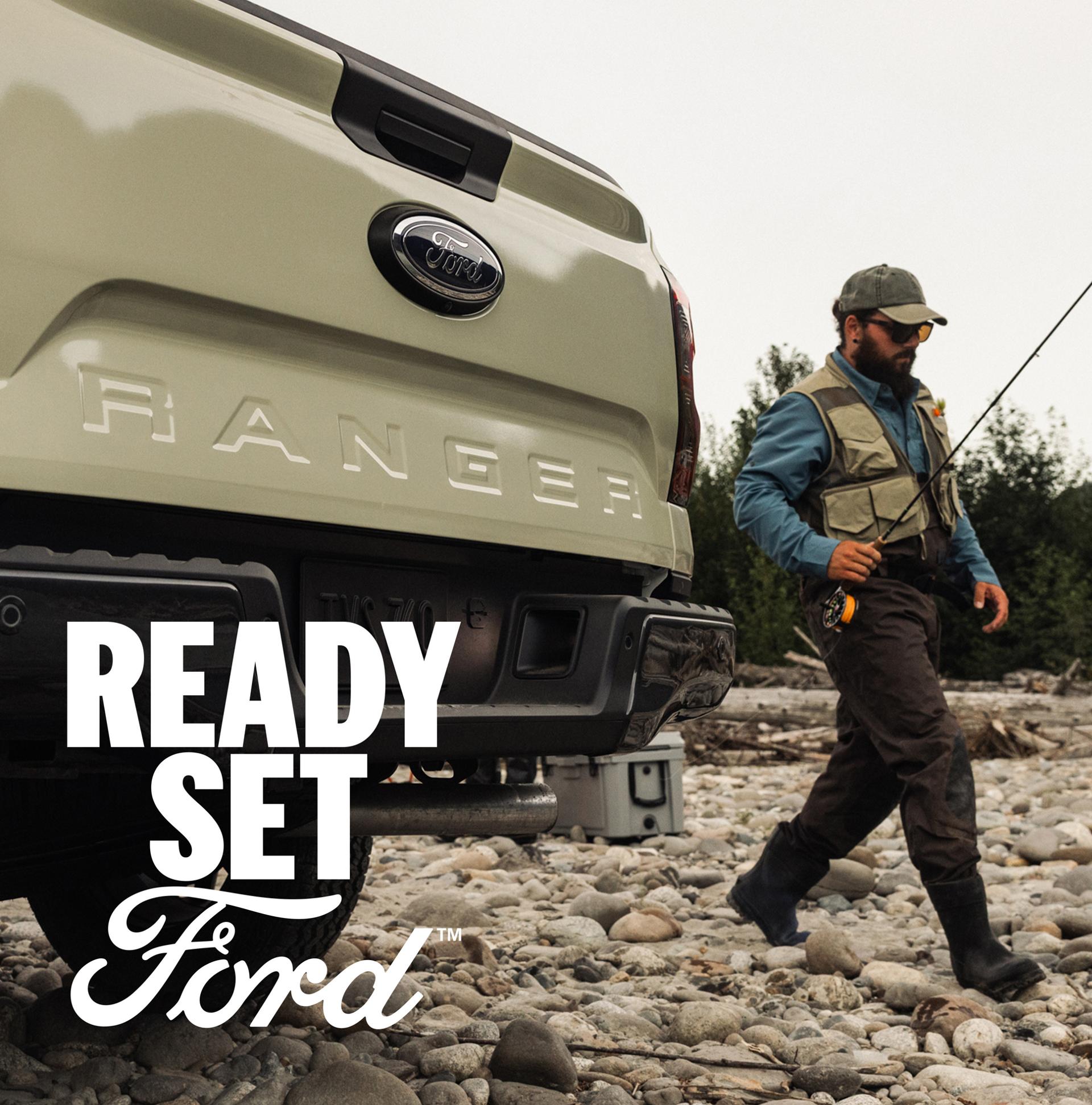 A person walking past the rear end of their 2026 Ford Ranger® truck with a fishing pole