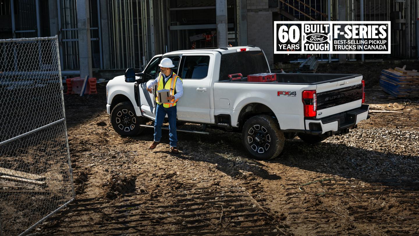 60 years. Built Ford tough. F-Series, best-selling pickup trucks in Canada. Construction worker stands next to a white Ford Super Duty truck at a construction site. 