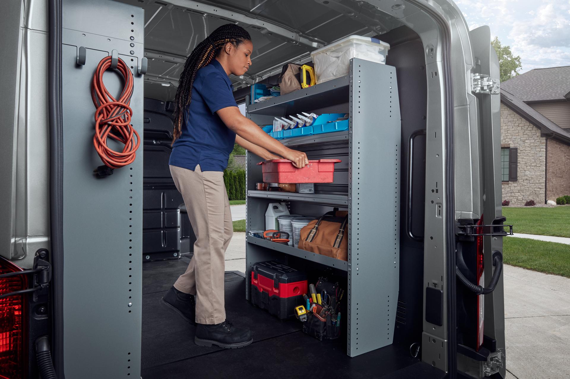 Rear view of a trades person working inside the rear doors of a 2027 Ford Transit® van