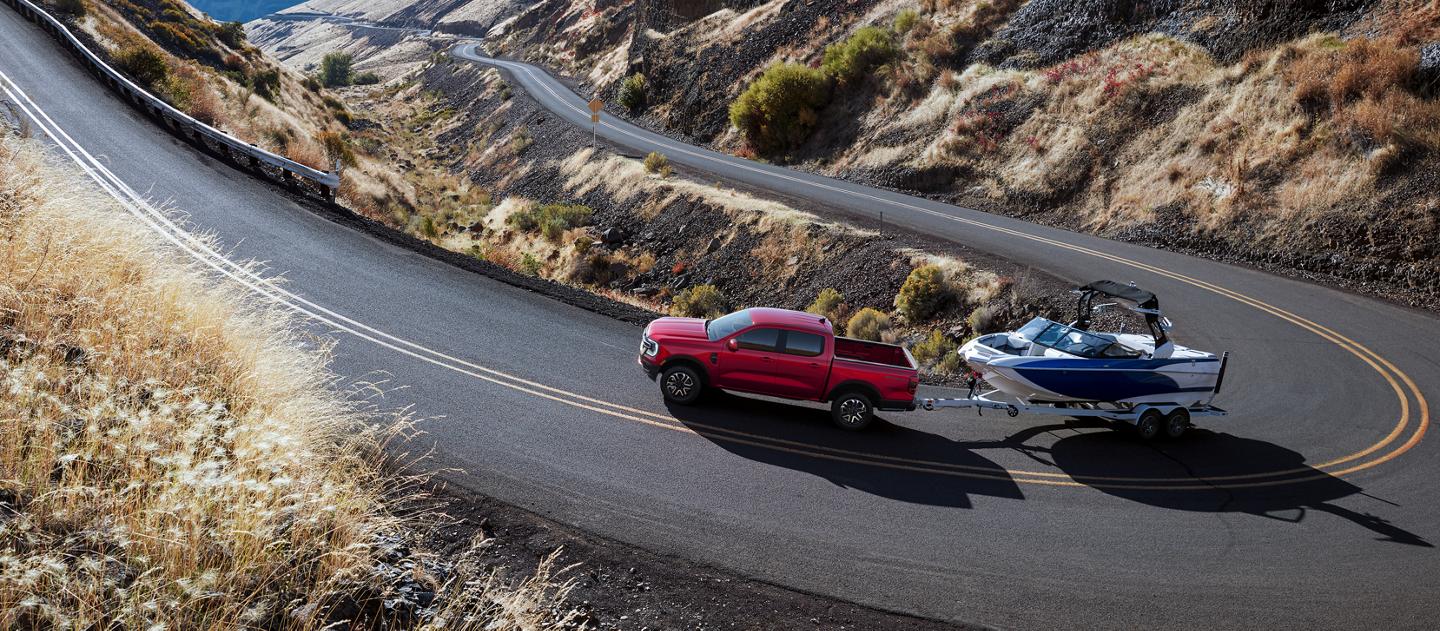 A 2026 Ford Ranger® truck towing a speedboat on a winding mountain road
