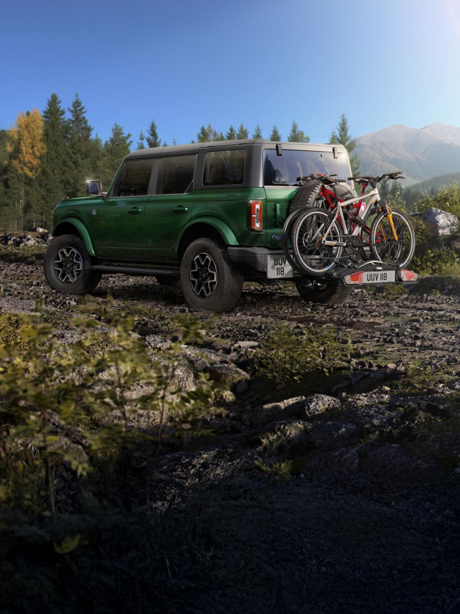 Bronco with rear-mounted bikes parked on a trail.