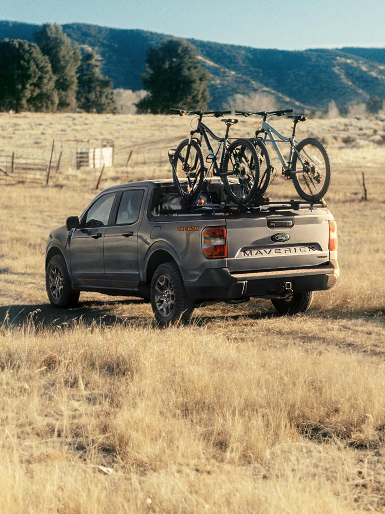 A 2026 Ford Maverick® Tremor® being driving on a dirt road with two bikes in the cargo bed