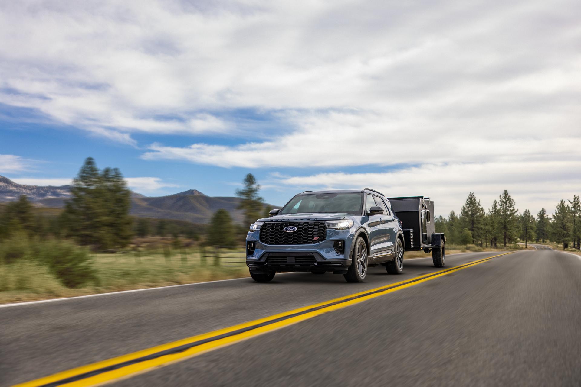 A 2026 Ford Explorer® SUV pulling a trailer on a highway through the mountains