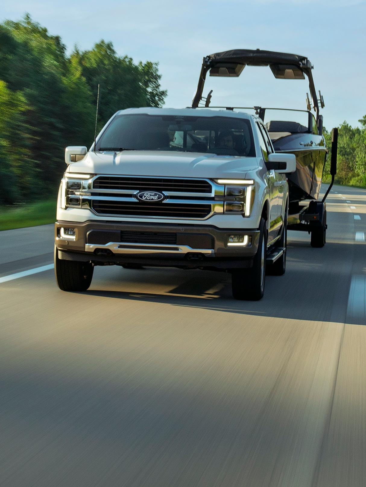 A 2027 Ford F-150® Lariat® pickup pulling a boat on a highway