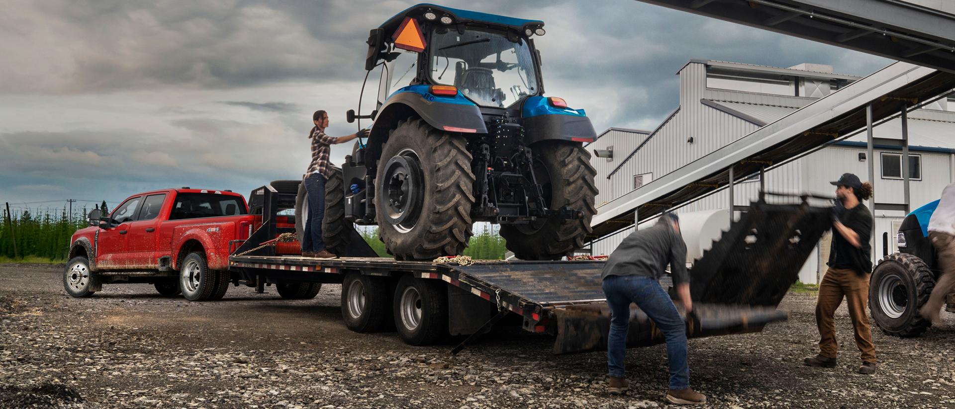 2027 Ford Super Duty® F-450® XL pickup in Race Red pulling a trailer carrying a large tractor