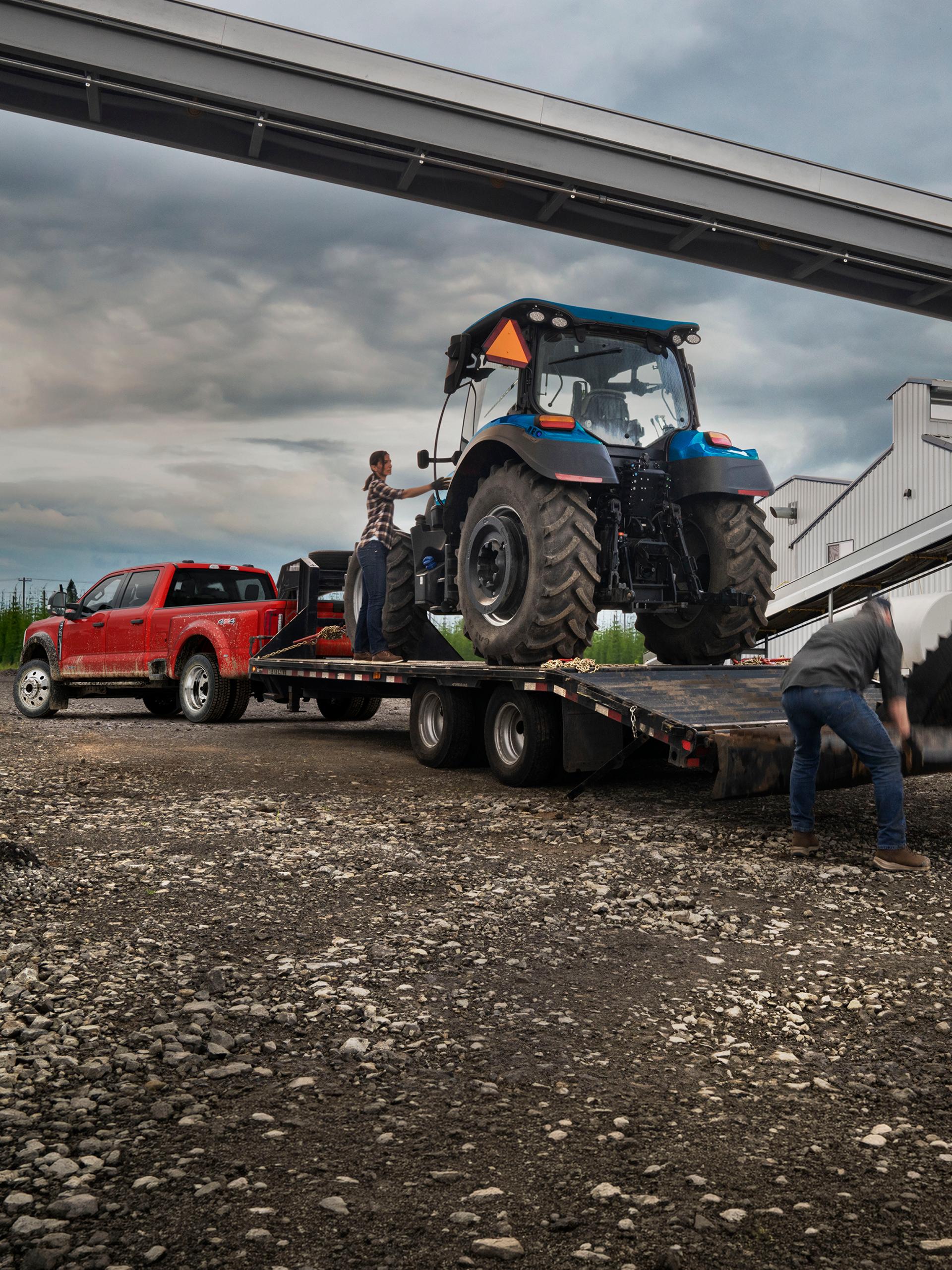 2027 Ford Super Duty® F-450® XL pickup in Race Red pulling a trailer carrying a large tractor
