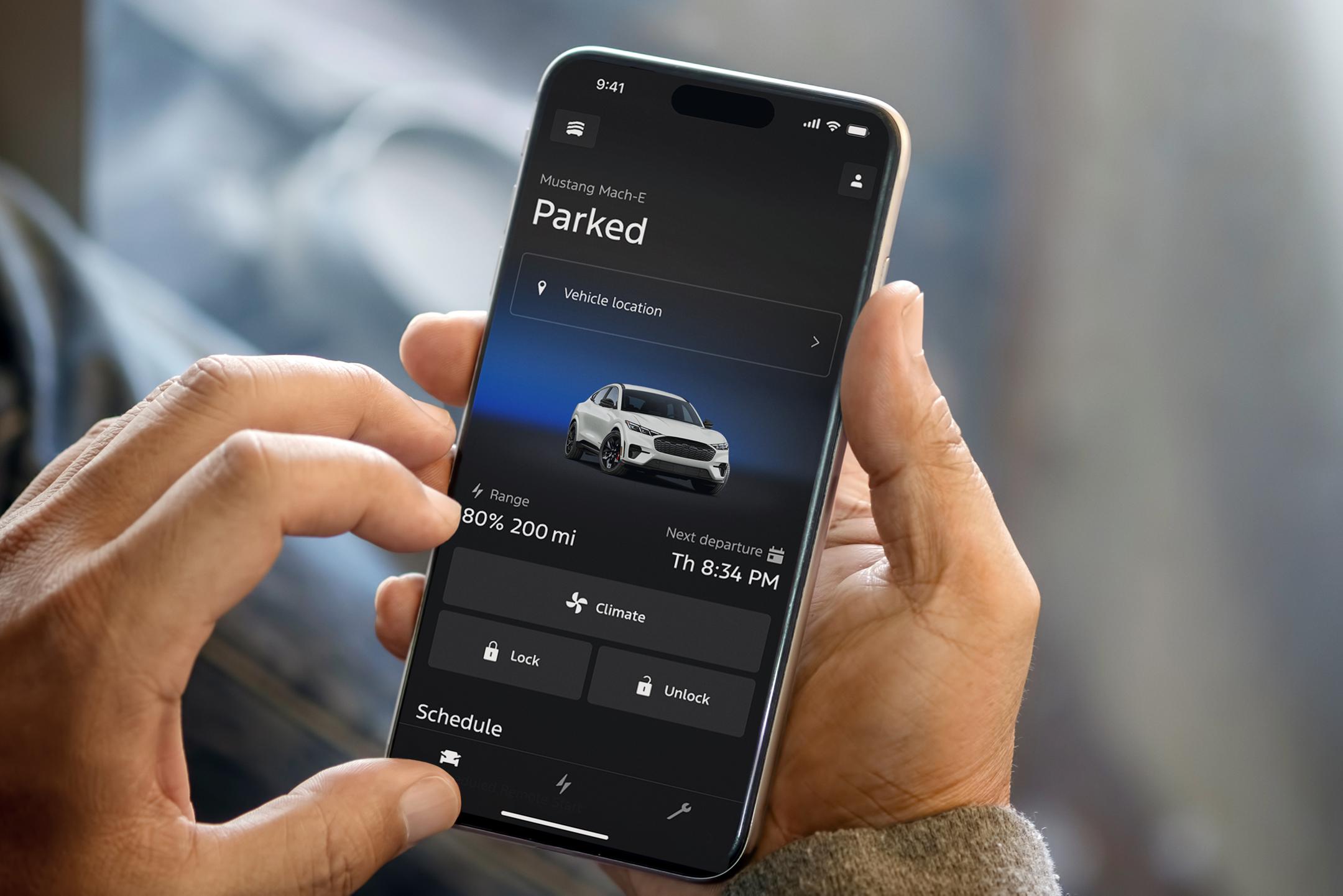 Person holding a smart phone displaying vehicle status.