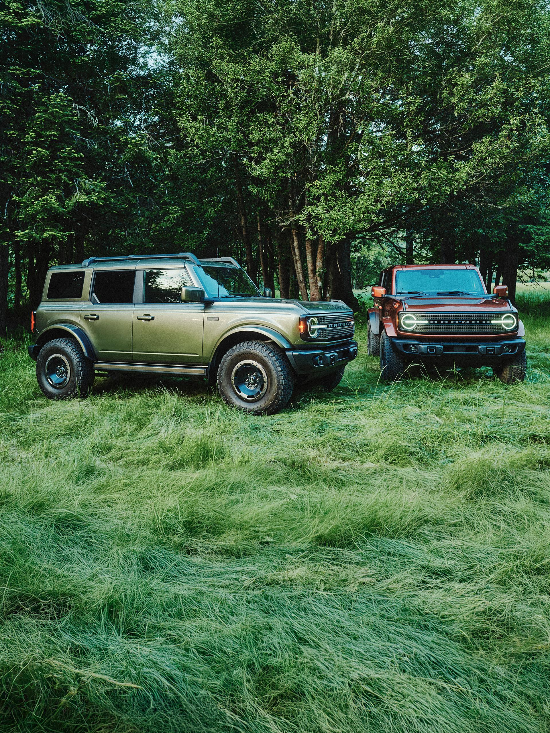 Two 2027 Ford Bronco® Filson SUVs parked in a grassy clearing