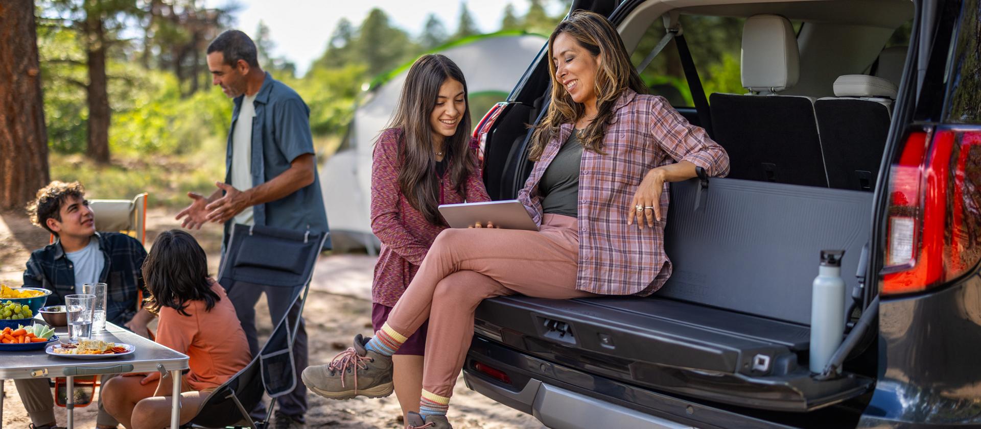 Two people using the available Cargo Tailgate Manager backrest in a 2026 Ford Expedition® SUV