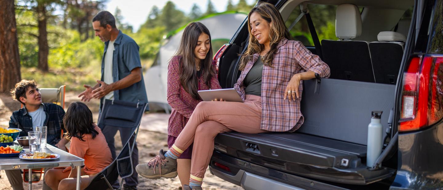 Two people using the available tailgate backrest in a 2026 Ford Expedition® SUV