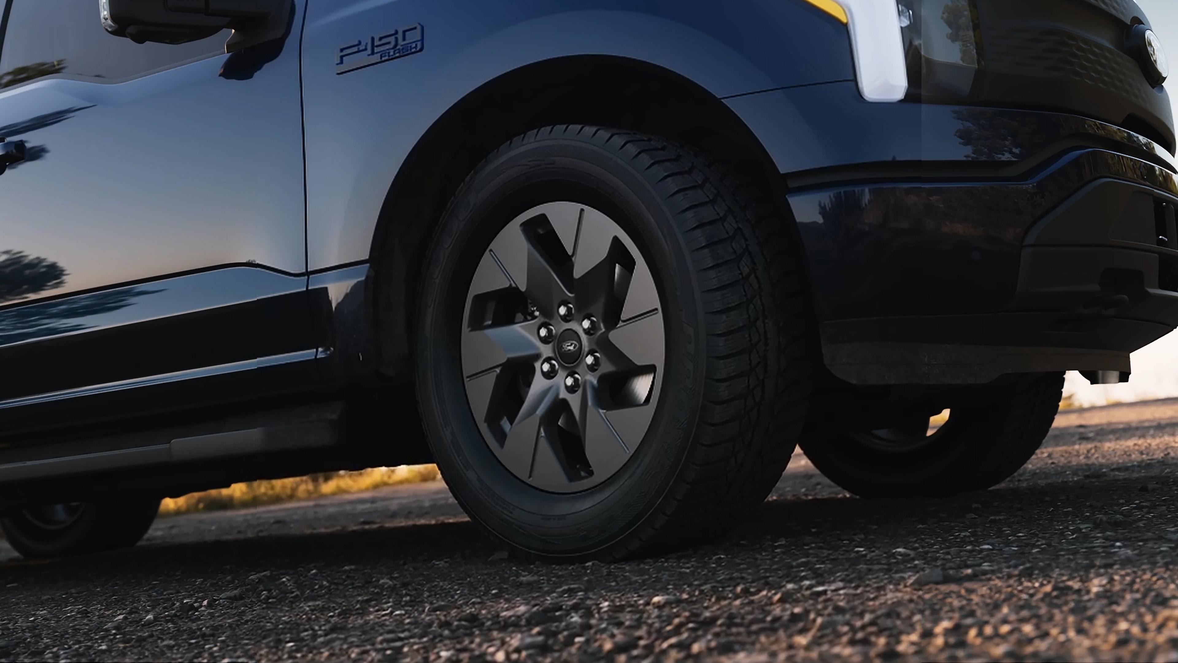 An exterior look at the 2025 Ford F-150® Lightning® Flash™ trim parked on a paved road in antimatter blue