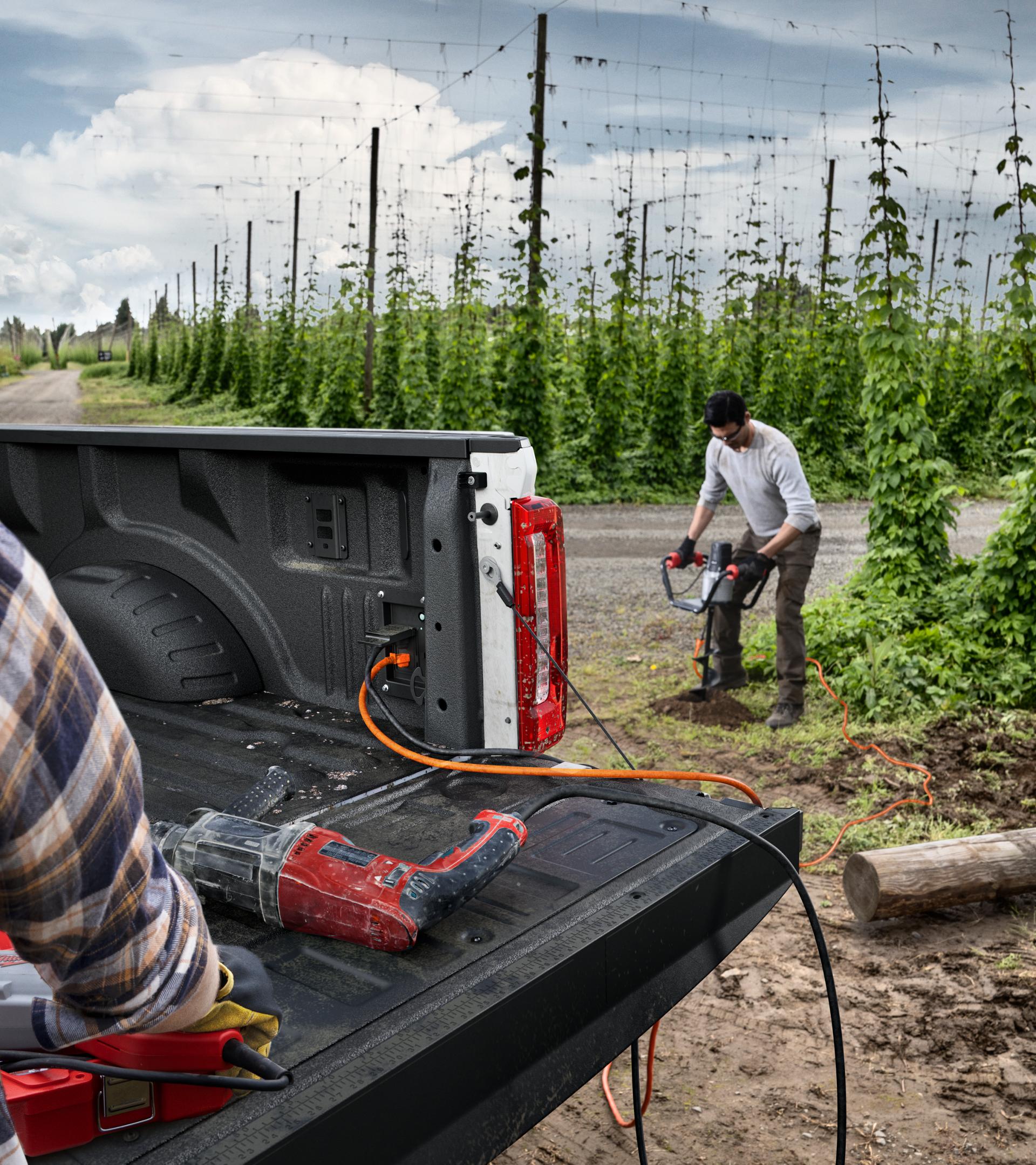 Two people with power tools using a 2026 Super Duty® F-350® XLT truck's in-bed outlets and 2kW Pro Power Onboard™ feature