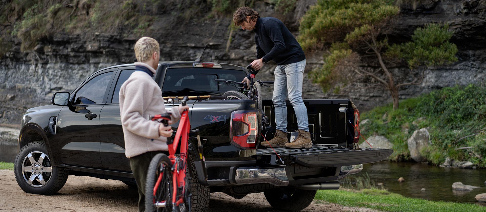 Two people loading gear into the bed of a black 2025 Ford Ranger® pickup