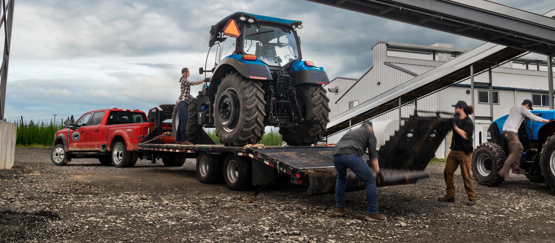 2026 Ford Super Duty® F-450® XL model in Race Red pulling a trailer with a heavy tractor on it