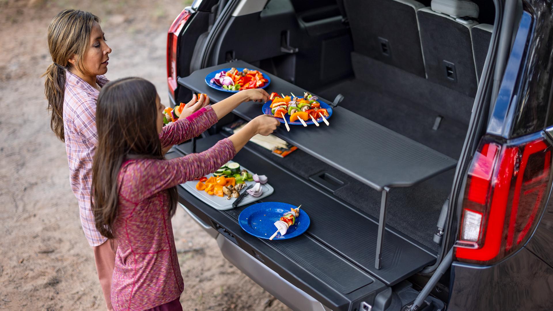 Two people using the available Cargo Tailgate Manager shelf in a 2026 Ford Expedition® SUV