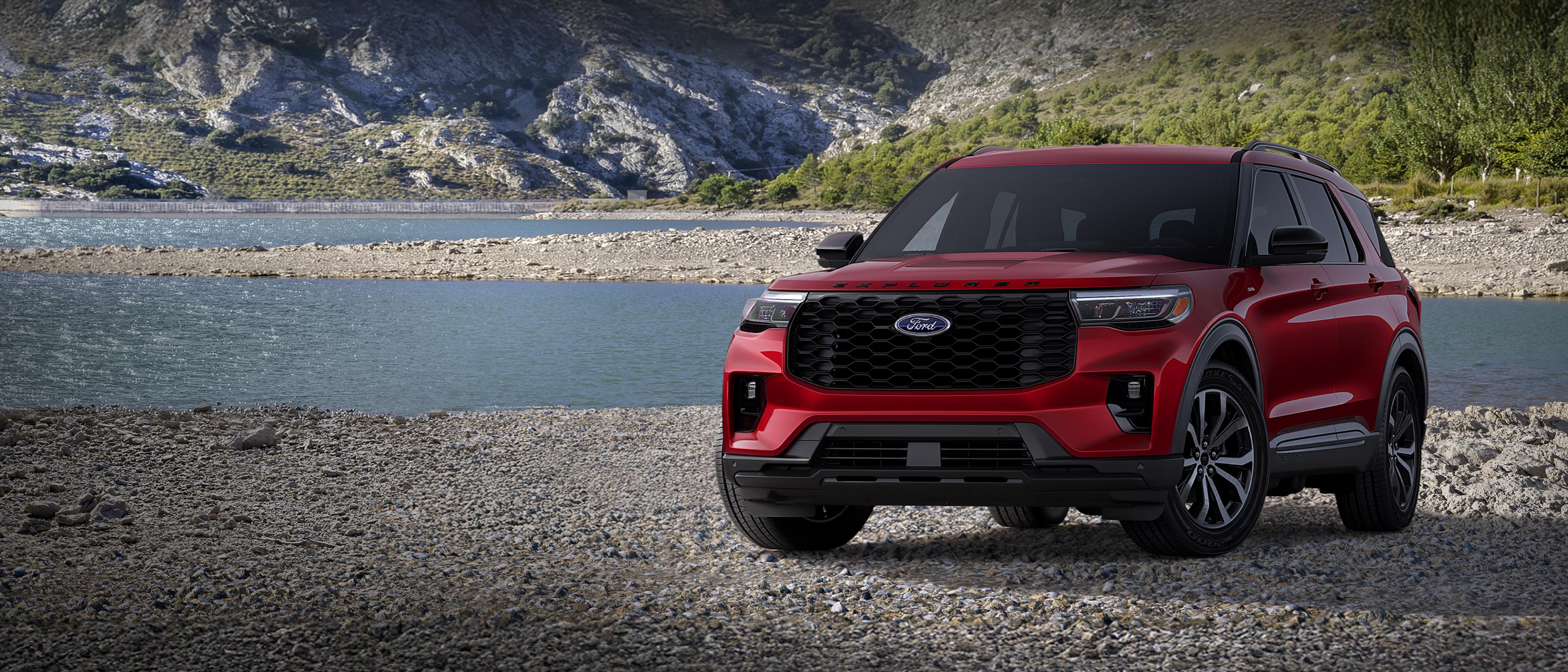 A 2026 Ford Explorer® ST-Line model parked on a rocky expanse near a mountain lake