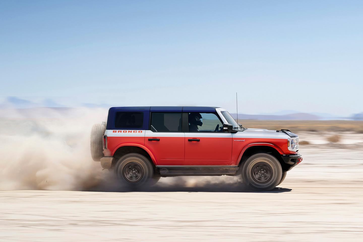 A 2026 Ford Bronco® Stroppe Edition SUV kicking up sand on a salt pan in the desert
