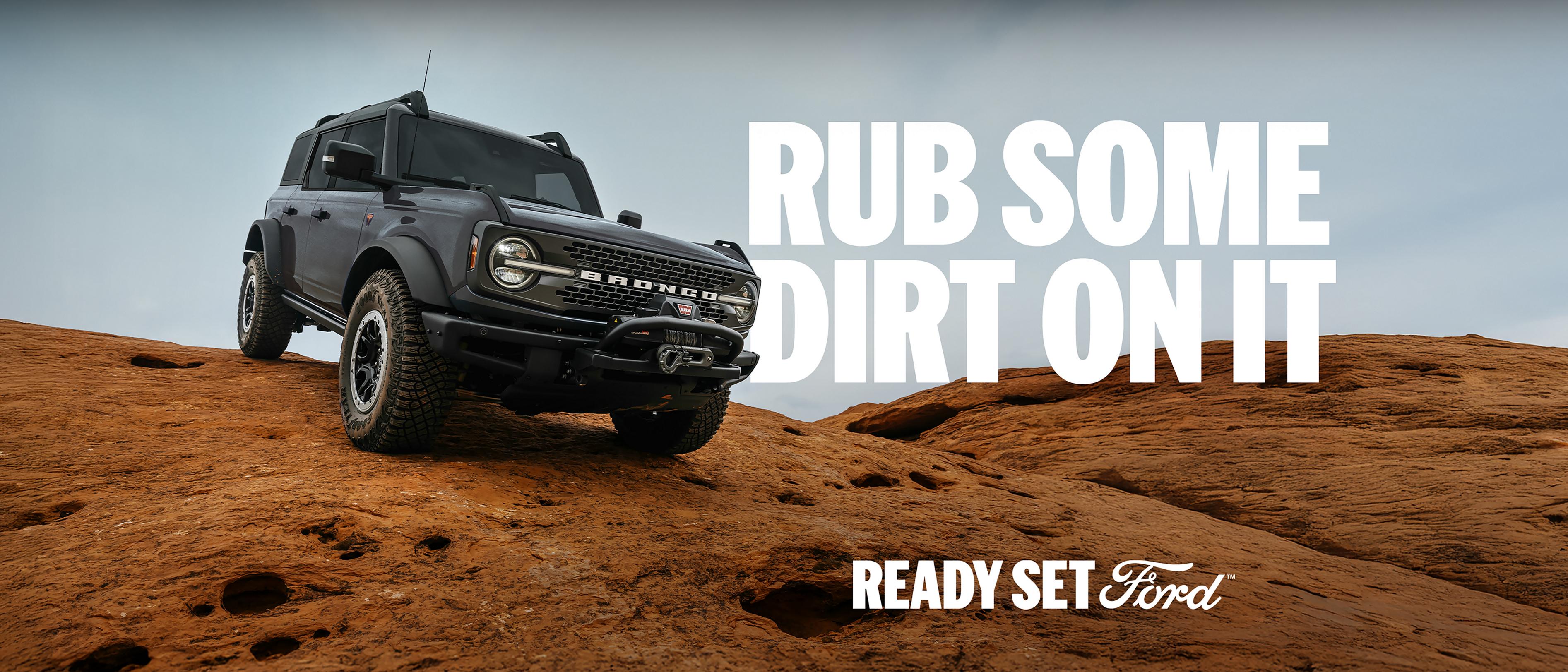 A 2026 Ford Bronco® SUV being driven down a dirt hillside. Caption: “Rub some dirt on it.”
