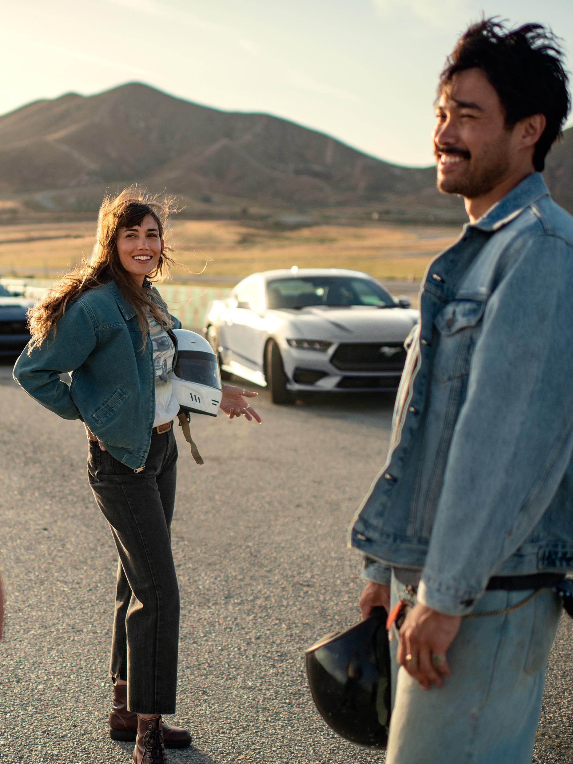 A 2025 Ford Mustang® coupe parked near a racecourse with two people nearby