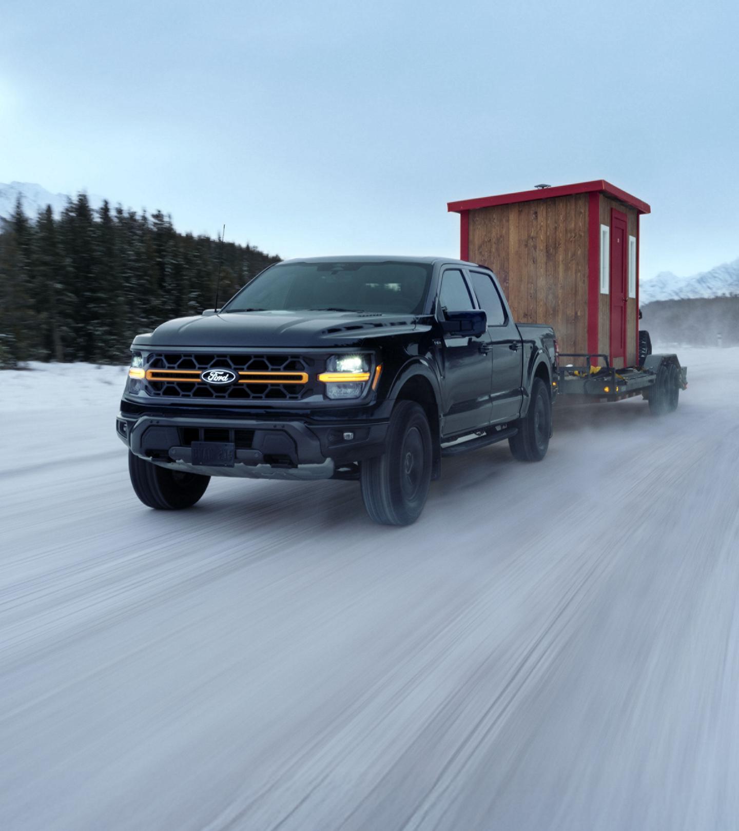 F-150 Tremor hauling an ice fishing hut and ATV on an icy mountain road.