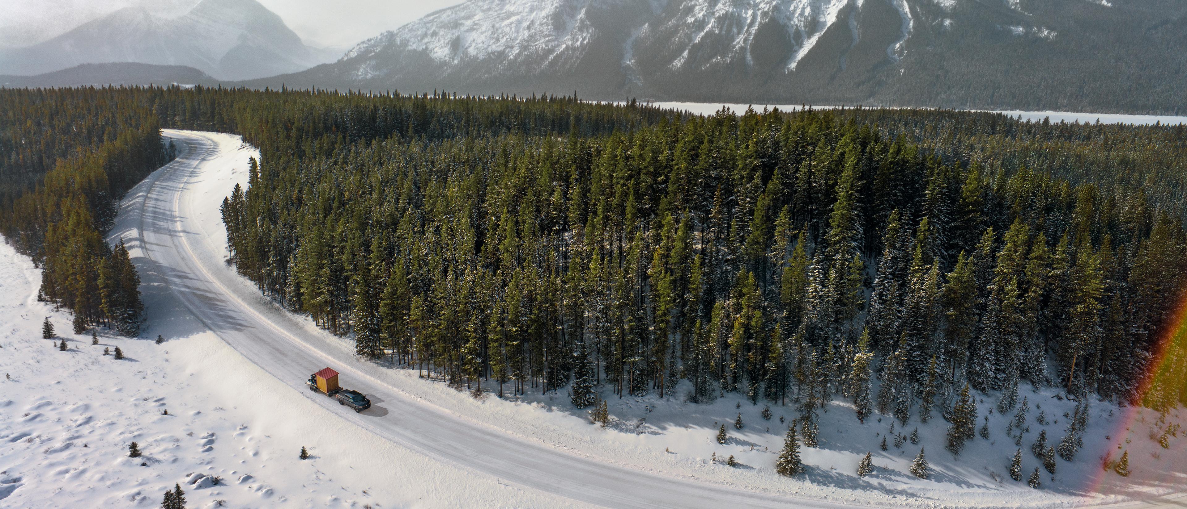 Aerial view of an F-150 Tremor hauling an ice fishing hut and ATV on an icy mountain road.