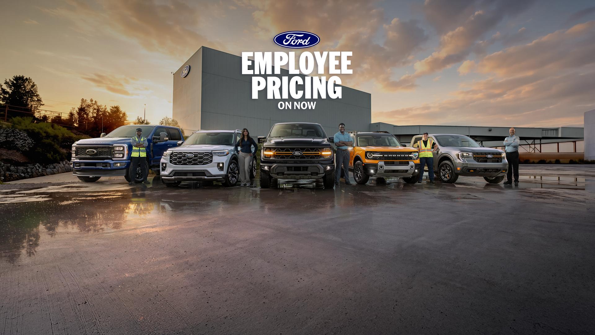 Ford employees standing beside Ford vehicles parked in front of the Ford Oakville Assembly Complex.