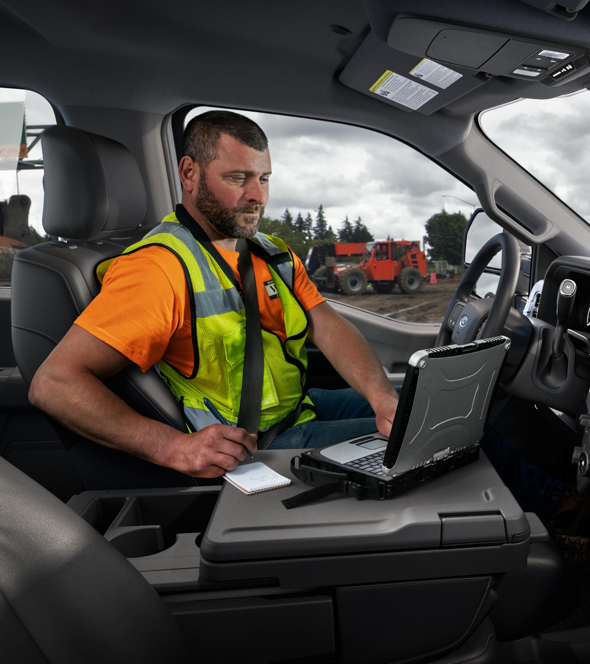 A person using a laptop with the interior work surface inside the cabin of their 2026 Ford Super Duty® F-250® XL model