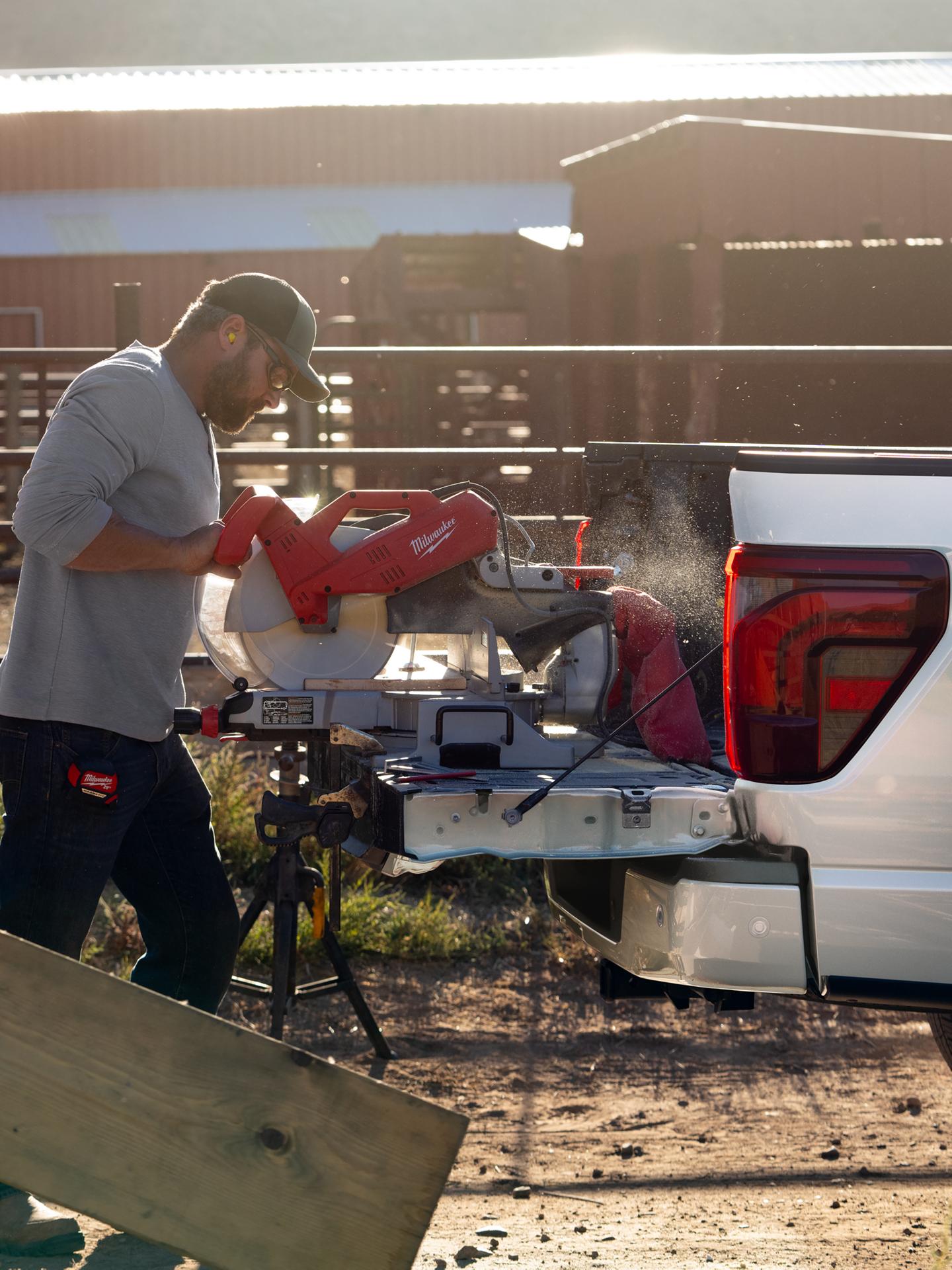 Man using a chop saw plugged into the Pro Power Onboard™ feature on the tailgate of a 2026 Ford F-150® truck