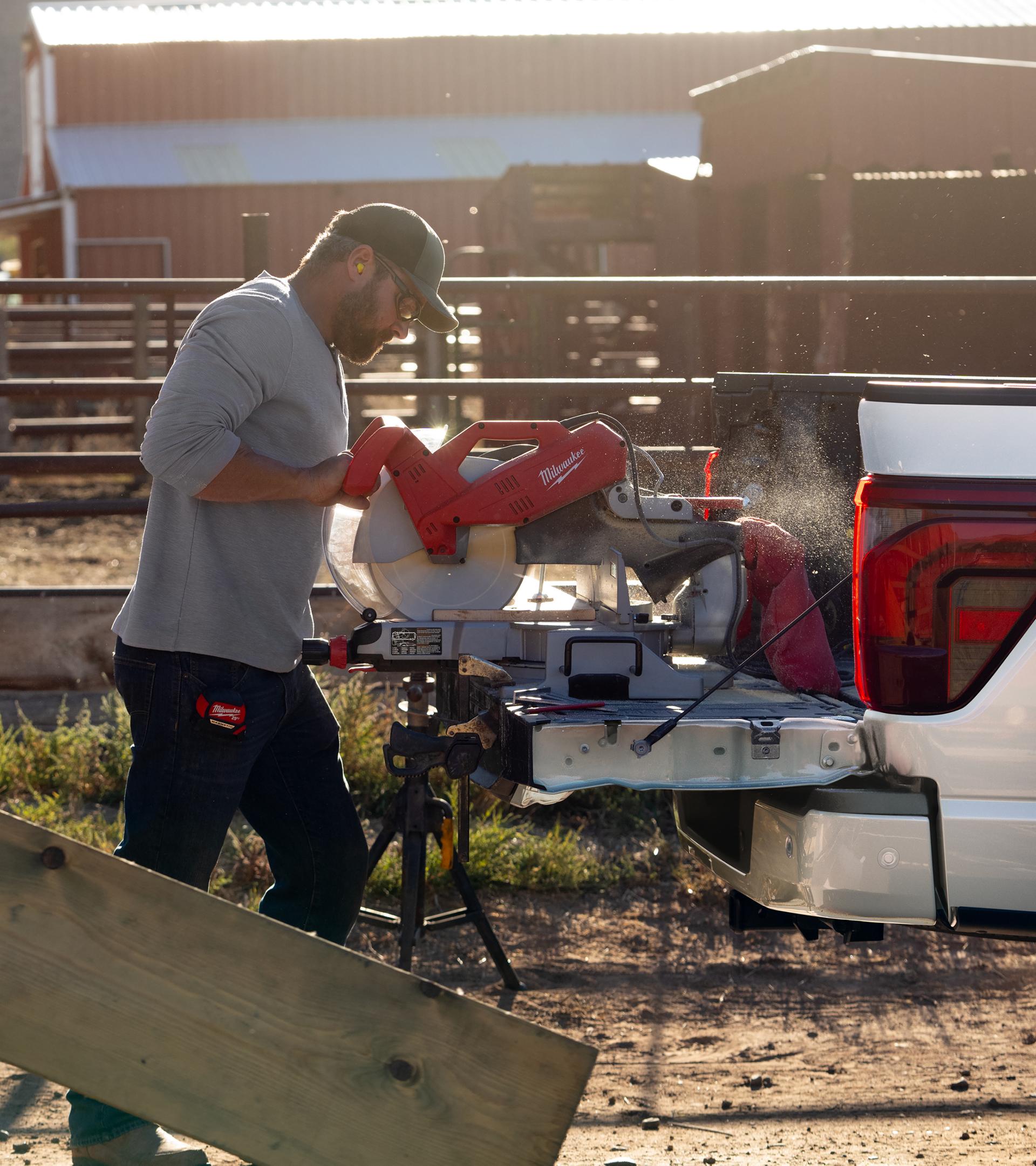 Man using a chop saw plugged into the Pro Power Onboard™ feature on the tailgate of a 2026 F-150® truck