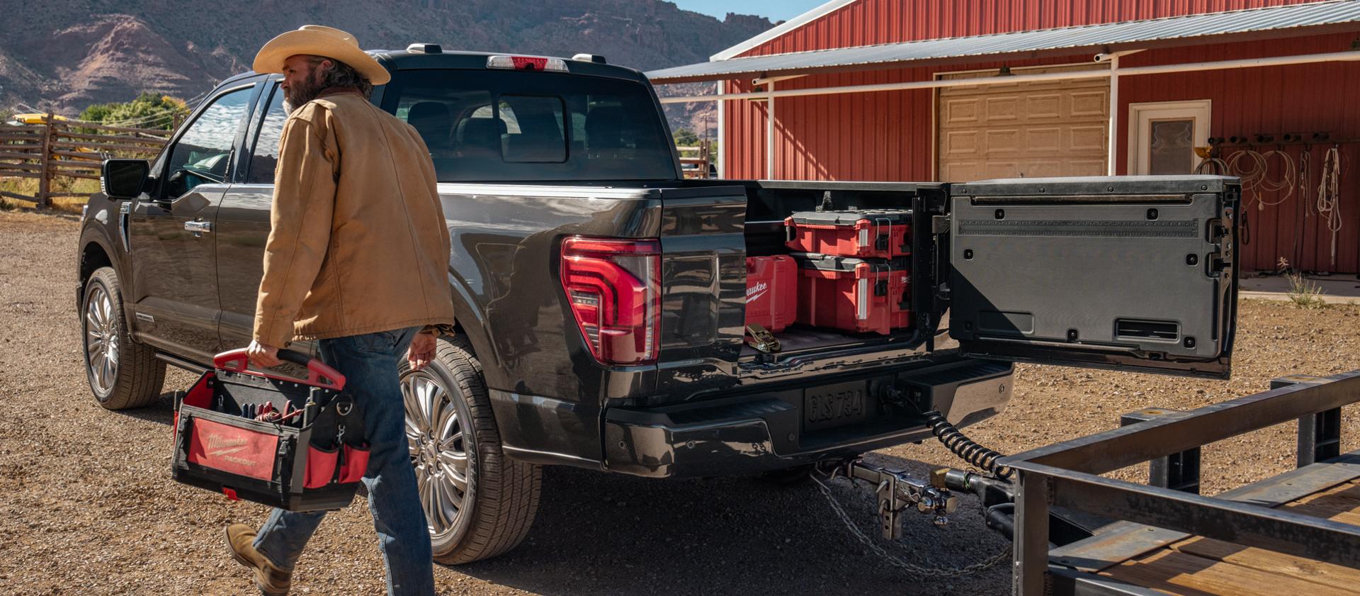 Man walking near a 2026 Ford F-150® Platinum® model with the Pro Access tailgate open showing tools in the bed