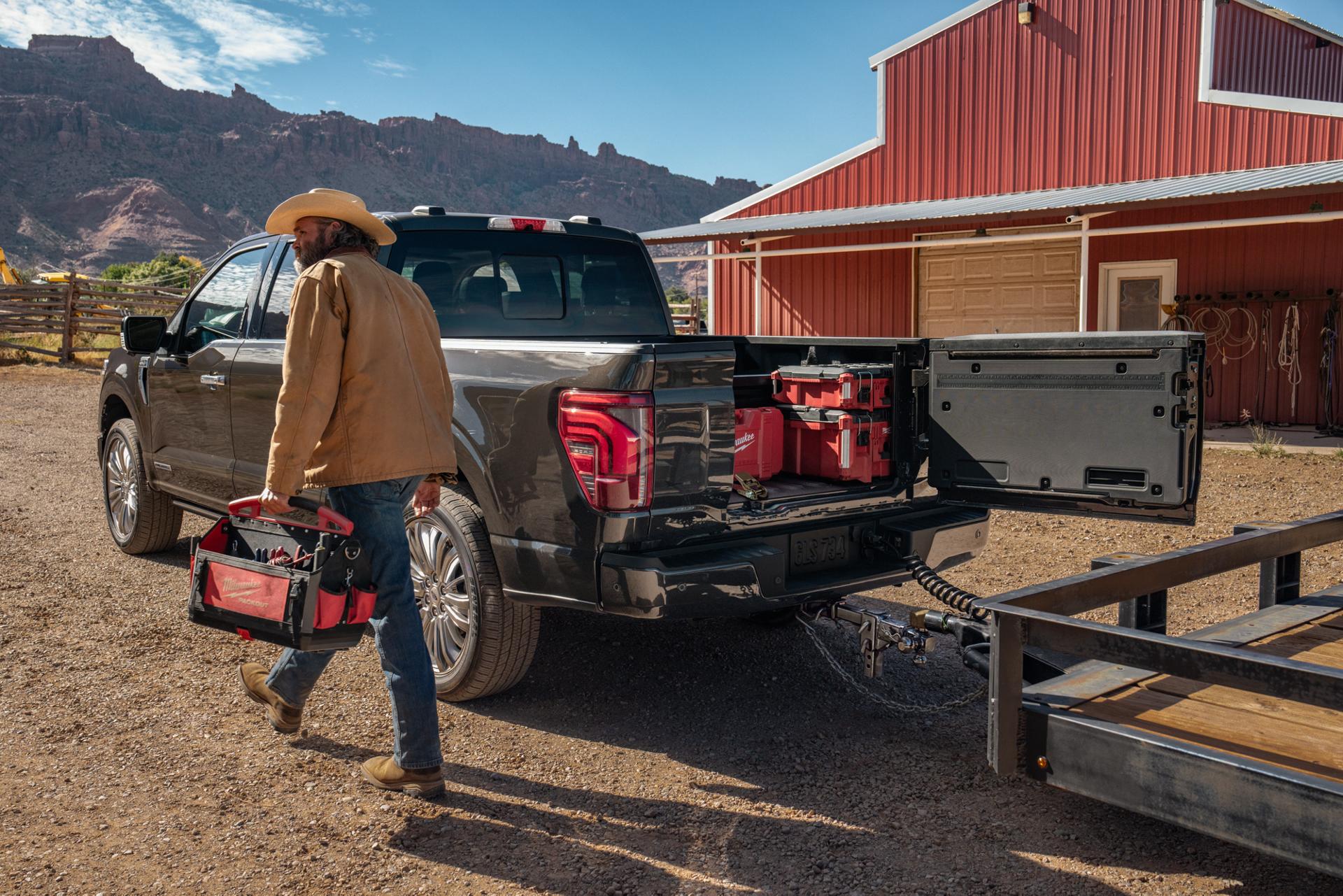 Man walking near a 2026 Ford F-150® Platinum® model with the Pro Access tailgate open showing tools in the bed