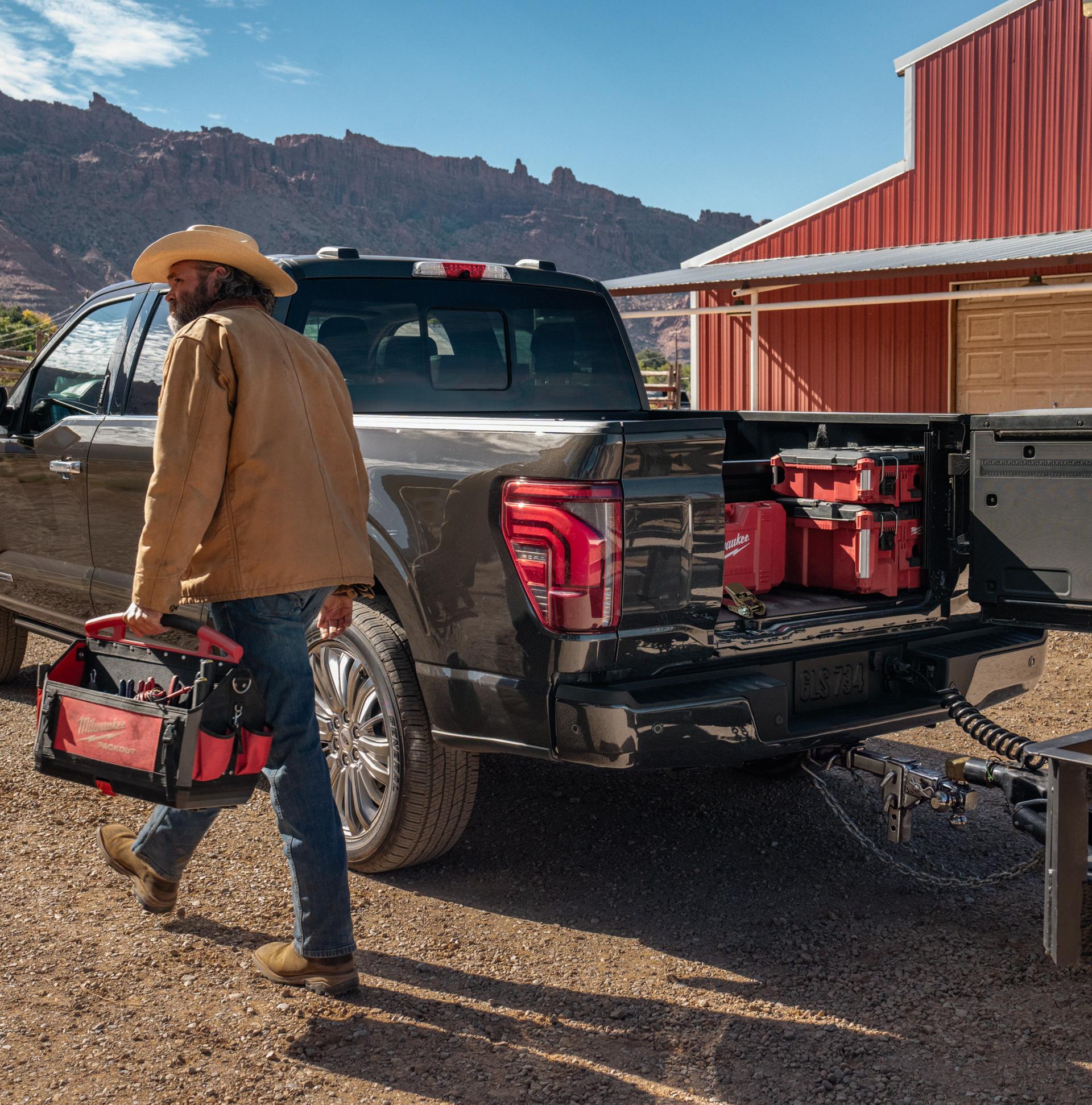 Man walking near a 2026 Ford F-150® Platinum® model with the Pro Access tailgate open showing tools in the bed