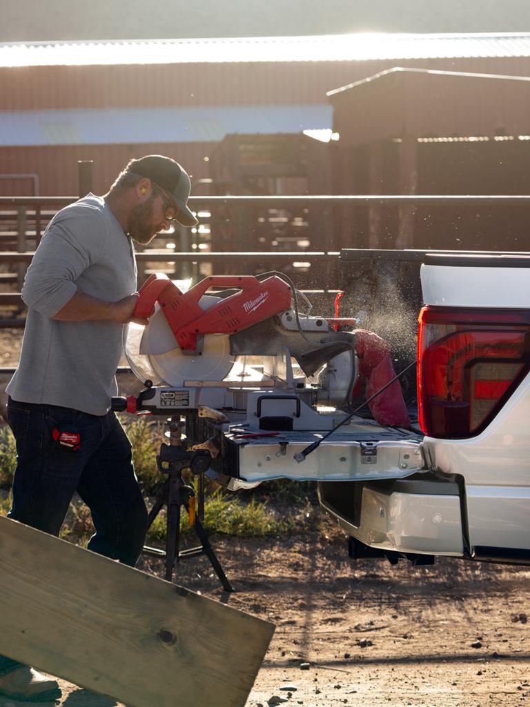 Man using a chop saw on the tailgate of a F-150® pickup while plugged into the Pro Power Onboard™ feature