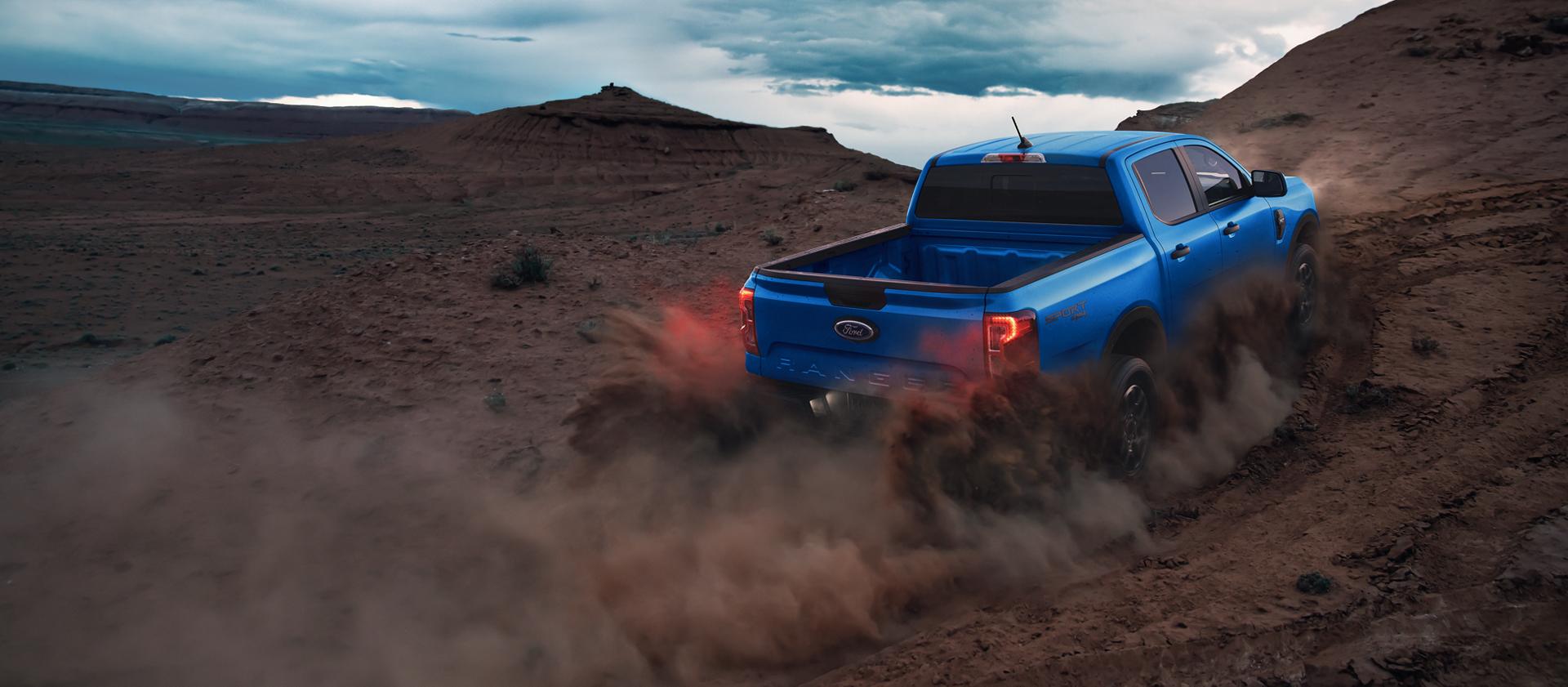 Rear view of a 2025 Ford Ranger® pickup being driven off, kicking up dust