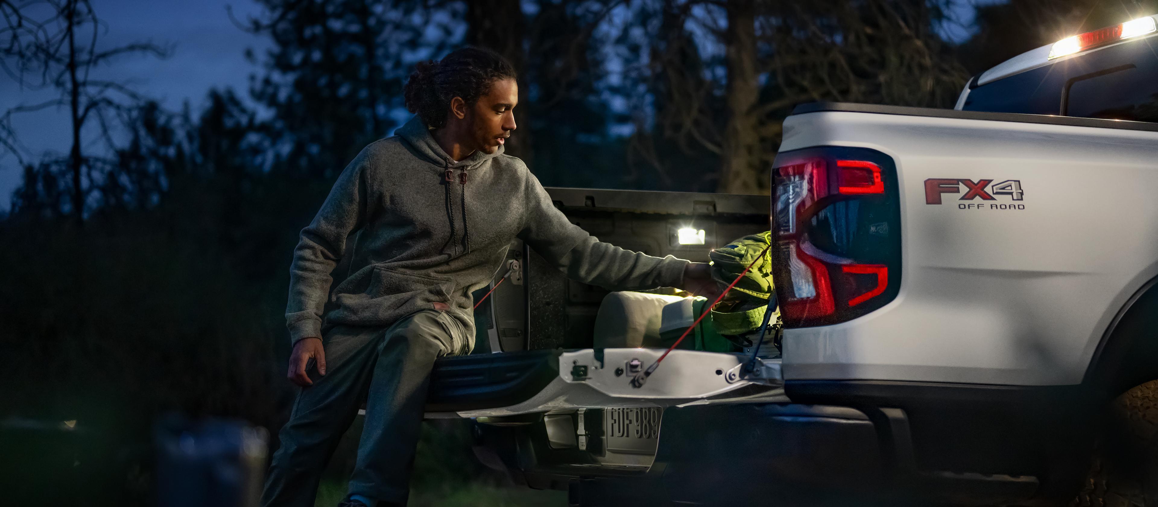 Exterior night shot showcasing LED bed lighting as person unloads gear from a 2025 Ford Ranger®