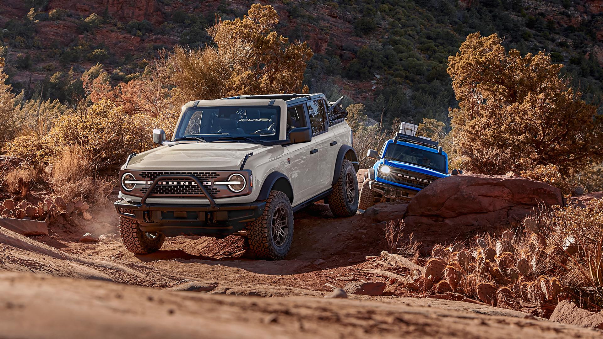 Two 2026 Ford Bronco® SUVs being driven on a scrubby dirt trail