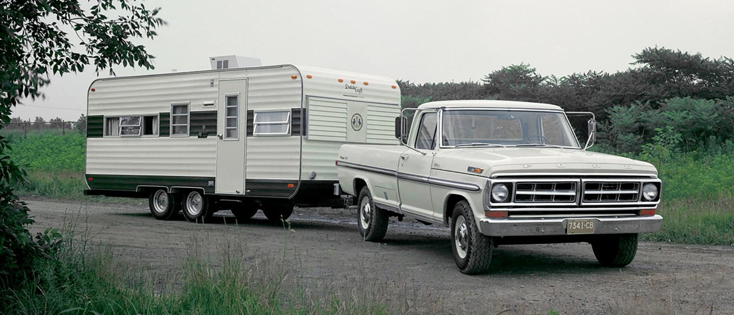 1970s F-150 with a hitched RV trailer.